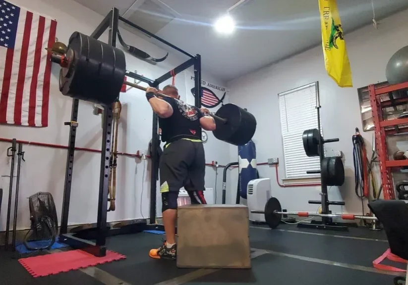 A man is lifting heavy equipment in the gym.